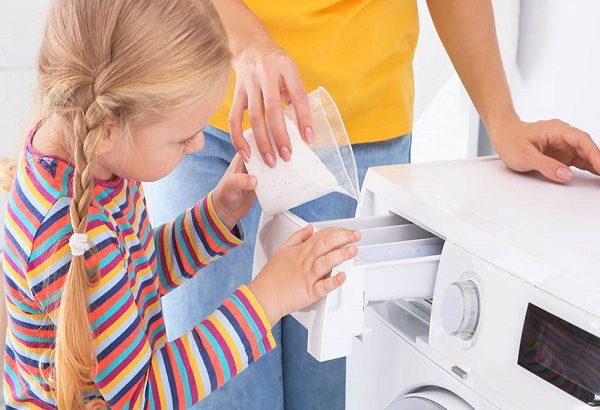 Little girl helping her mother to do laundry at home